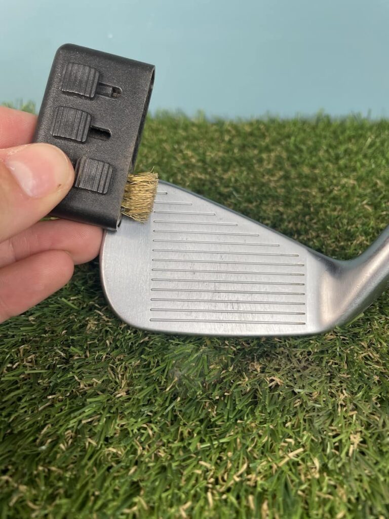 Giving the club face a final clean with a small brass cleaning accessory