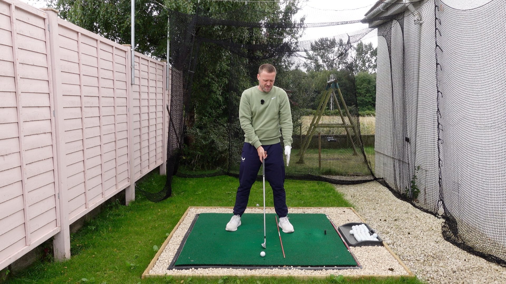 Golfer addressing the golf ball with alignment stick on left food