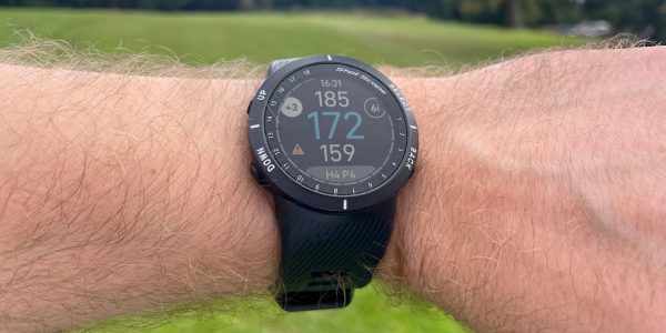 Shot Scope V5 GPS and shot-tracking golf watch on male wrist at the golf course.