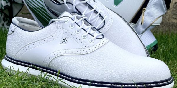 Image showing footjoy tradition golf shoes on the grass next to a golf bag.